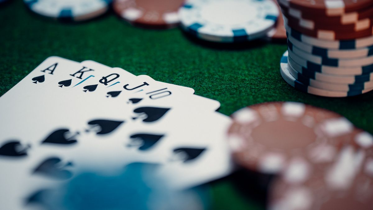 Kartu poker tersusun rapi di meja hijau bersama tumpukan chip